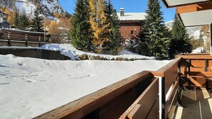 A snowy mountain landscape with a wooden deck overlooking a snow-covered area.