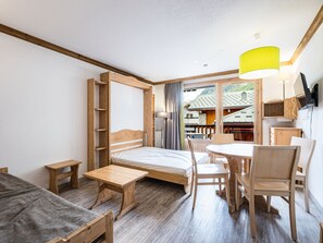 A compact room with a bed, a small table, a chair, and a desk. - Comfortable studio in the center with balcony (Val-d'Isère)