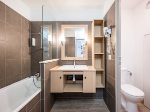 A modern bathroom with a bathtub, a sink with a mirror, and a toilet.