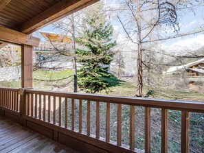 A wooden deck with a view of a mountainous landscape and a coniferous tree. - Charming apartment, ski-in/ski-out, parking included (Val-d'Isère)