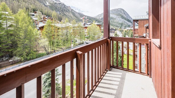 A balcony with a view of a mountainous area, wooden railings, and a stone wall. - Cozy mezzanine studio in Val-d'Isère center (Val-d'Isère)