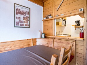 A wooden cabin interior with a bed, a small kitchenette, and a wall-mounted poster.