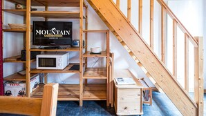 A wooden staircase leading to a loft area with a television, microwave, and shelves. - Cozy mezzanine studio in Val-d'Isère center (Val-d'Isère)
