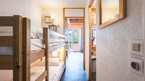 A narrow hallway with bunk beds on one side and a door leading to a room with a window. - Cozy mezzanine studio in Val-d'Isère center (Val-d'Isère)