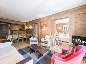Un vaste espace de vie comprenant une table à manger, des chaises, un canapé, un fauteuil rouge et un téléviseur.