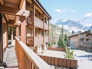 Ein Gebäude aus Holz mit Balkonen, einer Steinaußenwand und einer Bergkulisse.