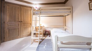 A bunk bed room with a wooden wardrobe, a small bedside table, and a lamp. - Cozy 3-bedroom apartment with direct piste access in Val-d'Isère (Val-d'Isère)