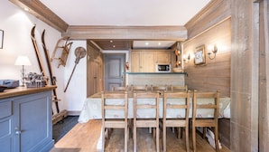 A rustic kitchen with wooden walls, a dining table with chairs, and a small island with a sink. - Cozy 3-bedroom apartment with direct piste access in Val-d'Isère (Val-d'Isère)