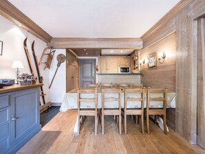 Una cucina rustica con pareti in legno, un tavolo da pranzo con sedie e una piccola isola con lavello.