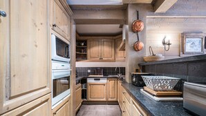 A kitchen with wooden cabinets, a stove, a sink, and a countertop. - Cozy 3-bedroom apartment with direct piste access in Val-d'Isère (Val-d'Isère)