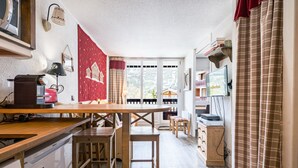 A compact kitchen with a wooden table, a refrigerator, a microwave, and a television on a stand. - Renovated Studio Cabin - Ski-in/Ski-out - WIFI (Val-d'Isère)