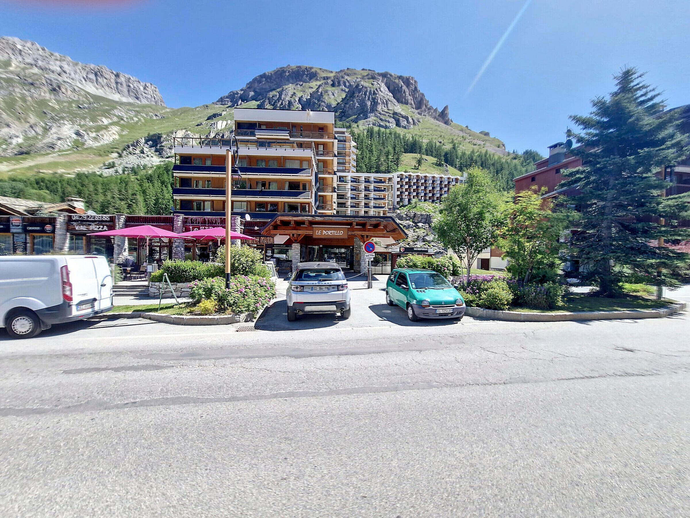 Un hotel con diversi piani, posti a sedere all'aperto e montagne sullo sfondo.
