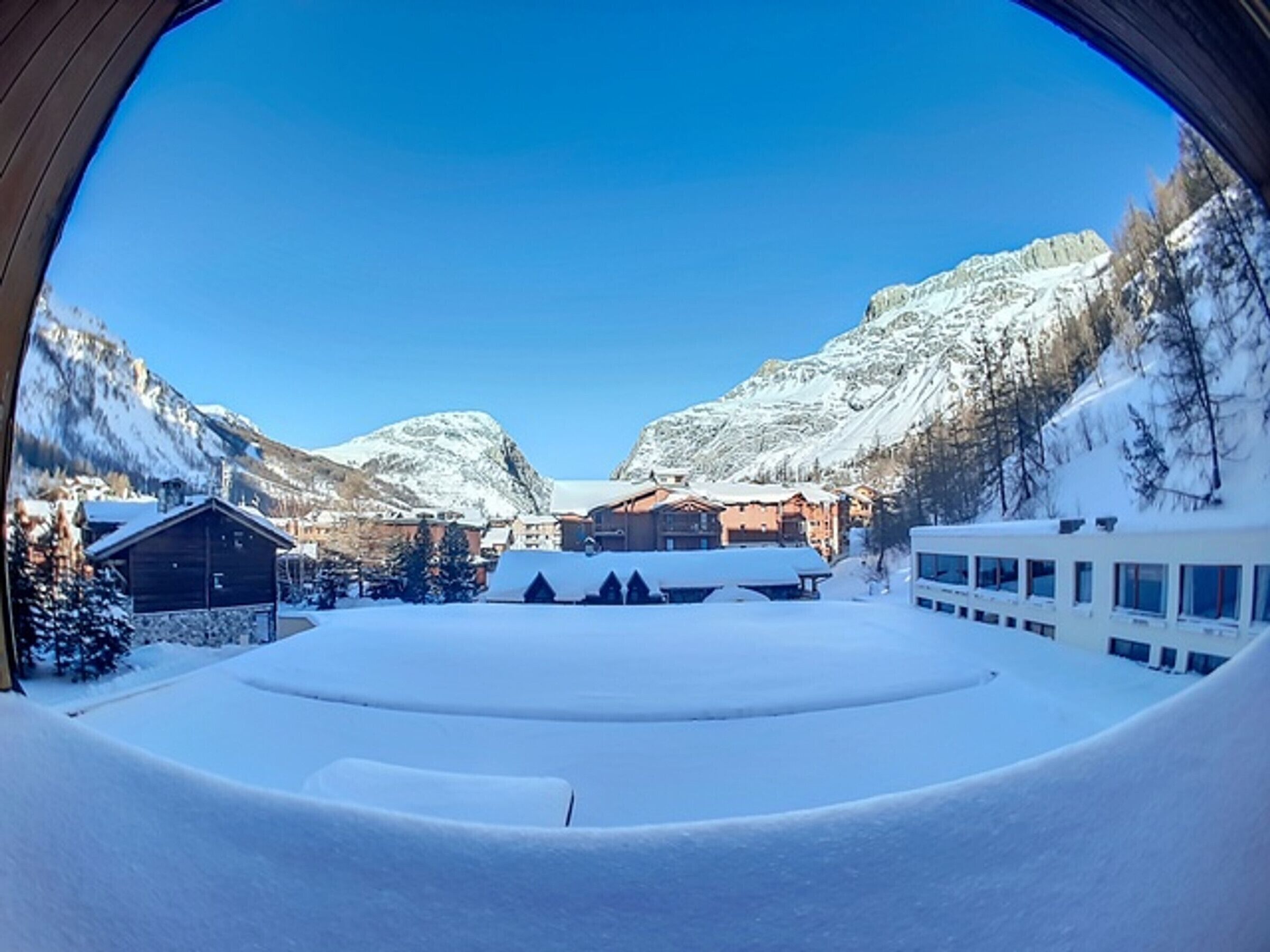 A snow-covered landscape with buildings and mountains.