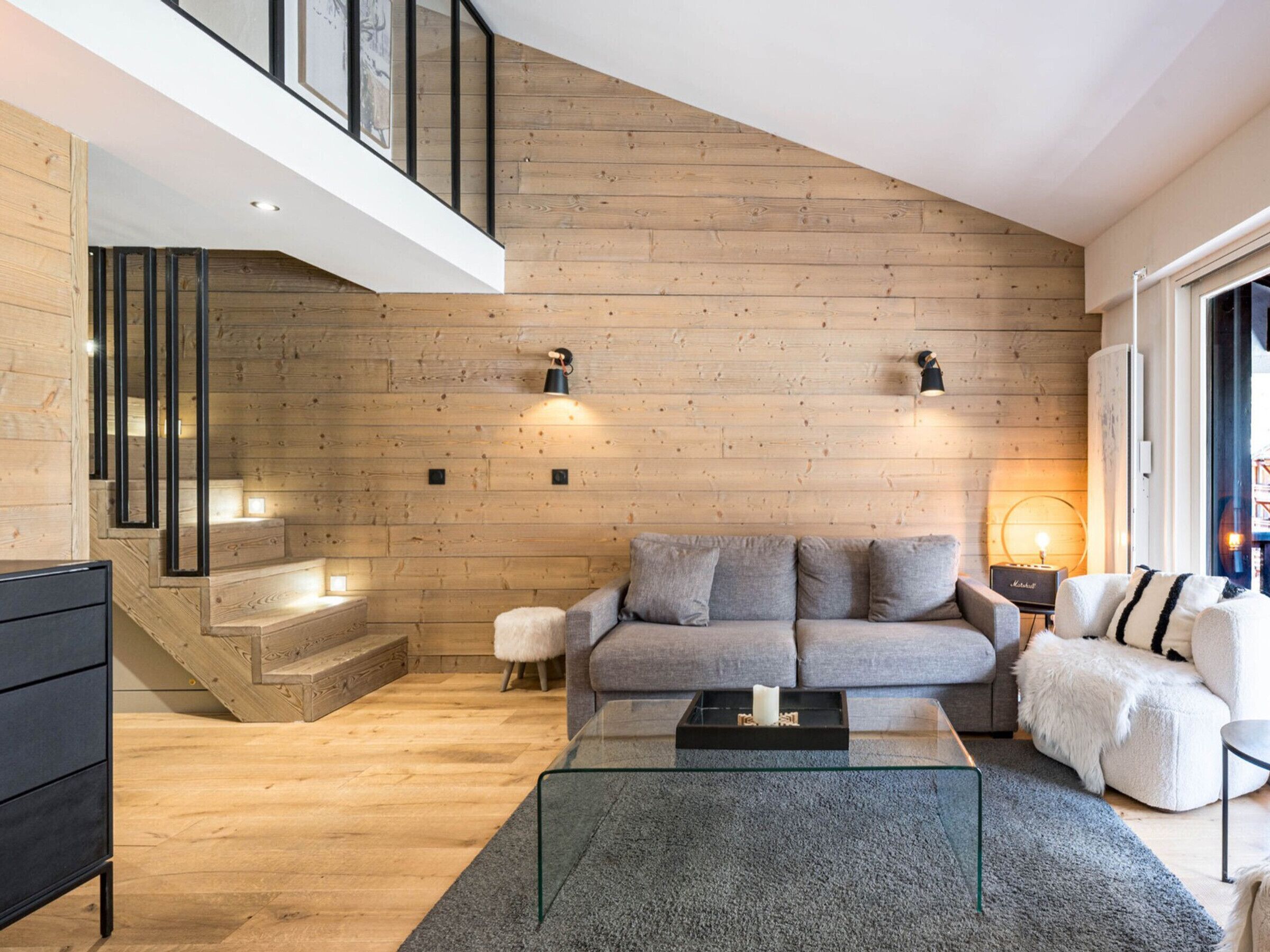 Una sala de estar moderna con una pared de madera, una mesa de centro de vidrio y un sofá.
