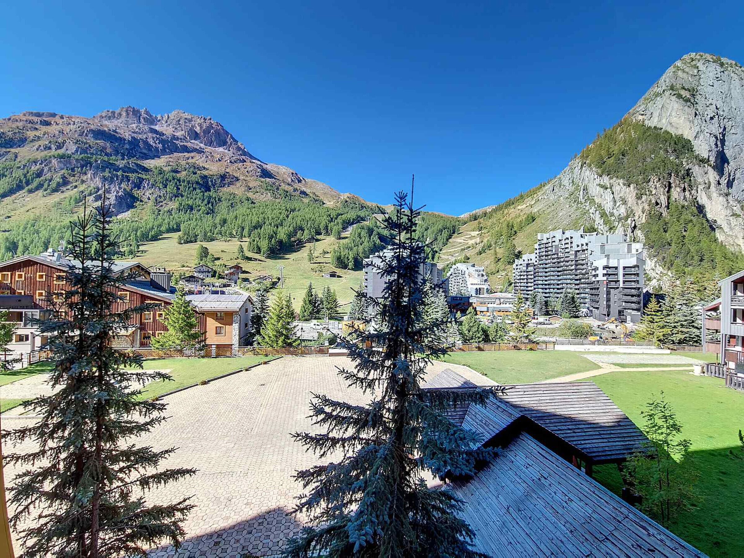 A mountainous landscape with a mix of residential and commercial buildings, including a large hotel with a wooden facade and a modern high-rise building.