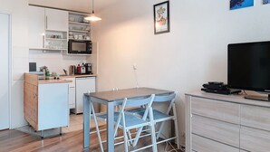 A compact kitchen with a dining area, a flat-screen TV, and a small dining table.