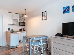 Cozinha compacta com área de refeições, televisão de tela plana e pequena mesa de jantar.