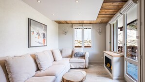 A modern living room with a sectional sofa, a round wooden coffee table, and a fireplace. - Renovated apartment, ski-in/ski-out, includes parking (Val-d'Isère)