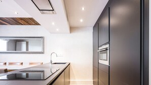 A modern kitchen with a central island, built-in oven, and a large mirror. - Renovated apartment, ski-in/ski-out, includes parking (Val-d'Isère)