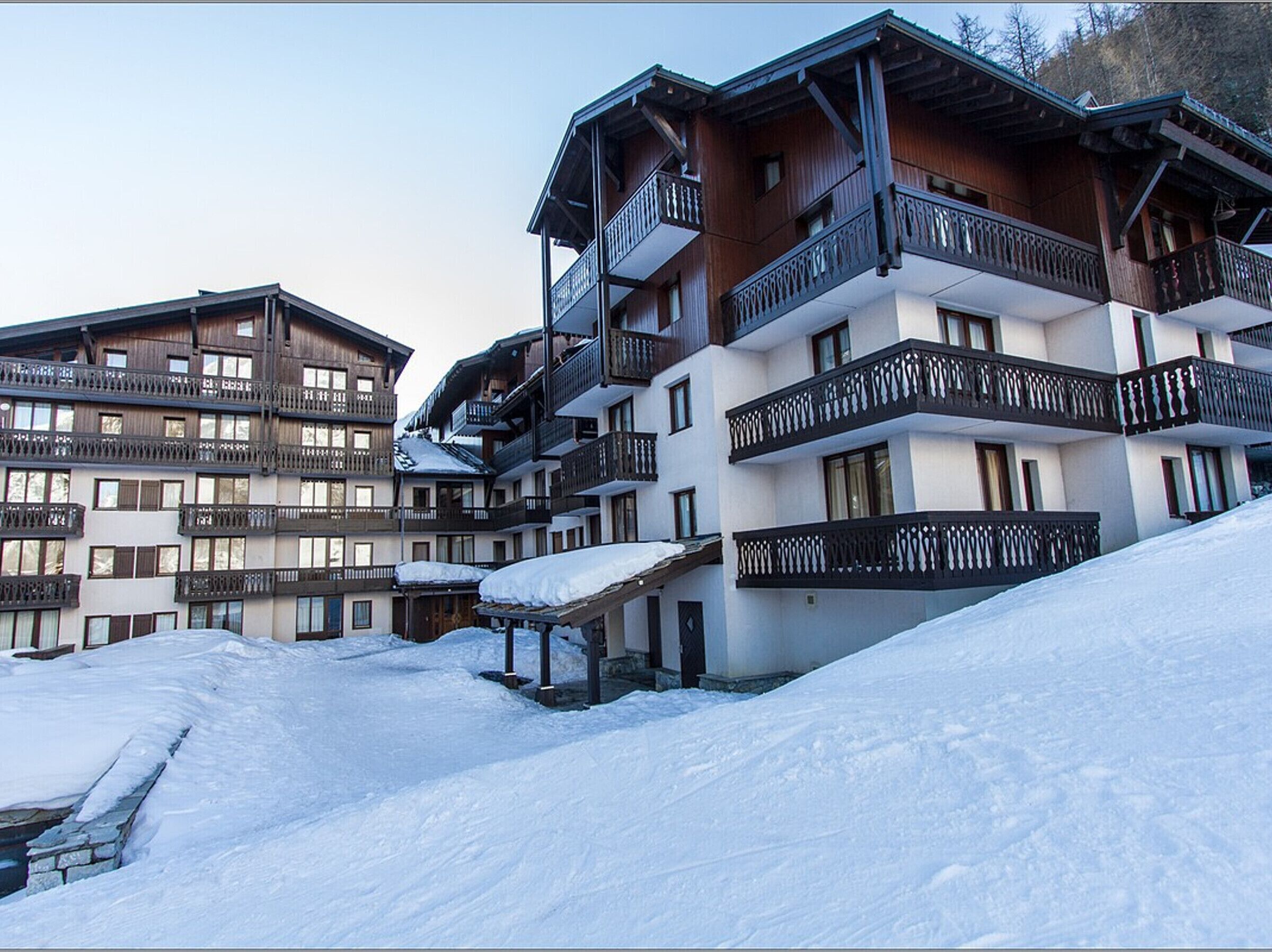 A multi-story hotel with balconies and a snow-covered landscape.