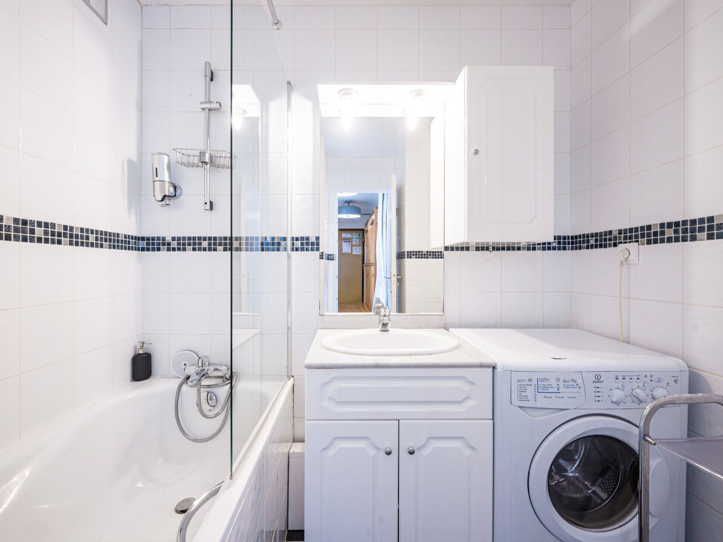 A modern bathroom with a bathtub, a washing machine, and a sink.