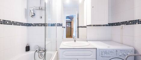 Une salle de bain moderne équipée d’une baignoire, d’un lave-linge et d’un lavabo.