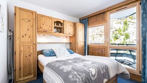 Una camera da letto con un letto, un armadio in legno e una finestra vista verde.