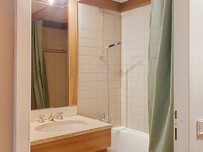 Un baño con lavamanos, espejo, ducha y bañera.