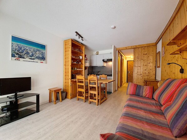 Una habitación acogedora con una mesa y sillas de madera, un sofá, un televisor y una cocina.