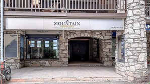 Un edificio de dos pisos con fachada de piedra y un letrero que dice "MOUNTAIN collection".