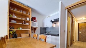 Una cocina compacta con una mesa y sillas de madera, un microondas y un lavavajillas.
