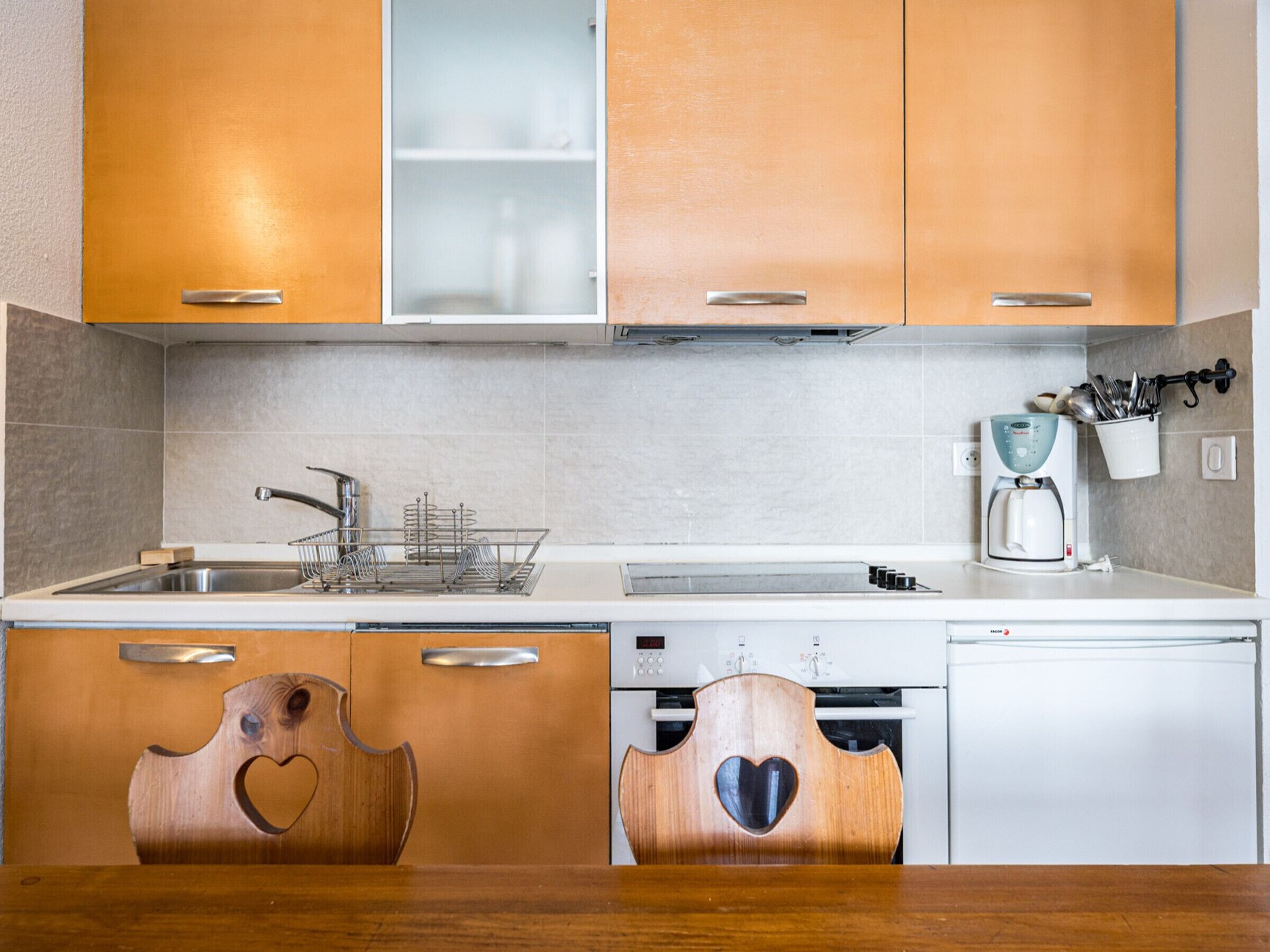 A kitchen with wooden cabinets, a sink, a coffee maker, and a dishwasher.