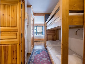 A narrow hallway with wooden walls and bunk beds.