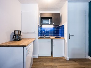 A compact kitchen with a coffee maker, microwave, and a sink.