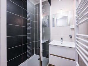 A modern bathroom with a glass shower enclosure, a white sink, and a mirror above it.