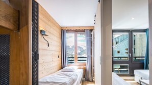 Une chambre avec un lit, une petite table et une vue sur un paysage montagneux.