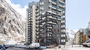Un immeuble à étages doté d’une architecture originale, avec des balcons et un paysage montagneux accidenté en toile de fond.