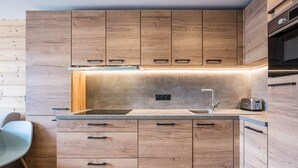 Une cuisine moderne avec des meubles en bois, une cuisinière encastrée, un évier et un grille-pain.