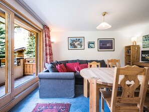 A cozy living room with a sofa, a dining table, and chairs, a bookshelf, and framed pictures on the wall. - Charming duplex 4p, 6 pers, parking, ski-in/ski-out (Val-d'Isère)