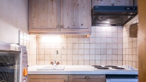 A kitchen with wooden cabinets, a white countertop, a built-in stove, and a dishwasher. - Comfortable studio in center, balcony, 2-3 pers. (Val-d'Isère)
