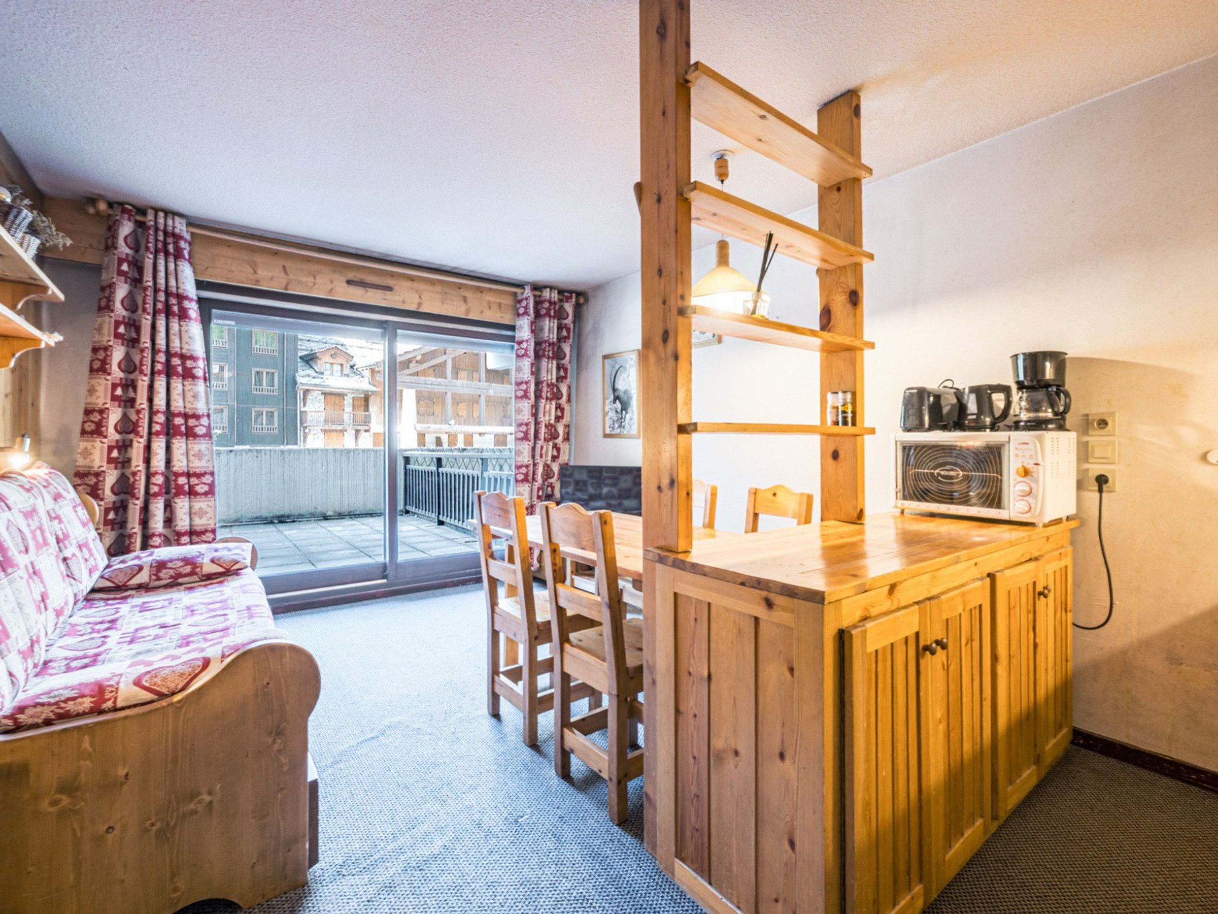 Eine gemütliche Küche mit Holzmöbeln, einem Essbereich und Blick auf einen Balkon.