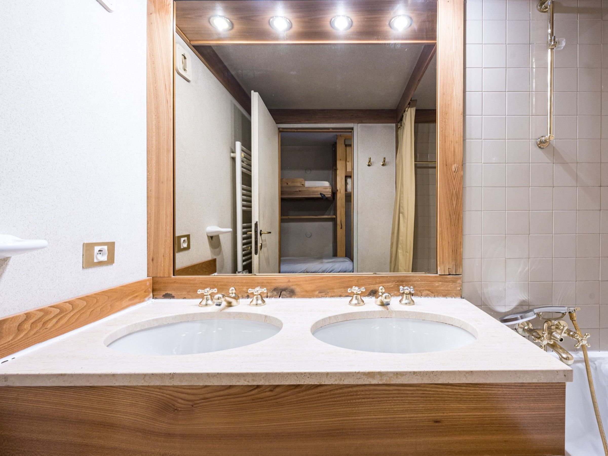 A bathroom with two sinks, a mirror, and a shower.