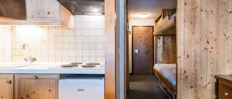 A compact kitchen with a Frigelux refrigerator, a stove, and wooden cabinets.