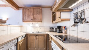 A compact kitchen with wooden cabinets, a built-in washing machine, a dishwasher, and a stove.