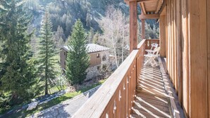 A wooden balcony with a view of a mountainous landscape.