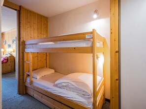 Quarto com beliches, paredes de madeira e uma luminária de cabeceira.