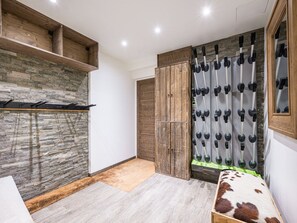 Ein Zimmer mit Steinwand, Holzregalen, einem Kleiderschrank und einem Spiegel mit Holzrahmen.