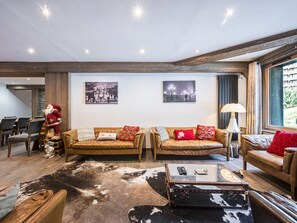Ein modernes Wohnzimmer mit Ledersofas, einem Glastisch und einem Kragenfuss-Teppich.
