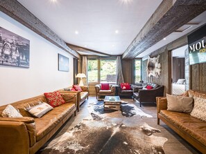 A spacious living room with leather sofas, a cowhide rug, and a large window providing a view of the outdoors. - Renovated Apartment Center Val d'Isère - 6 Rooms, 10 Pers, Parking (Val-d'Isère)