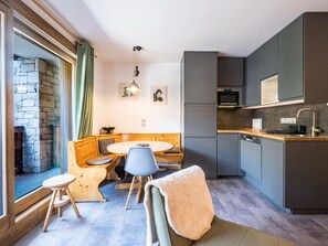 A compact kitchen with a dining area, stone wall, and modern appliances. - Renovated apartment with slope access and covered parking (Val-d'Isère)